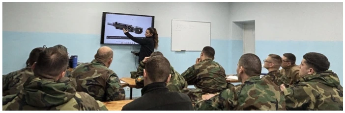 Instructor teaching a group of trainees using a technical illustration on screen